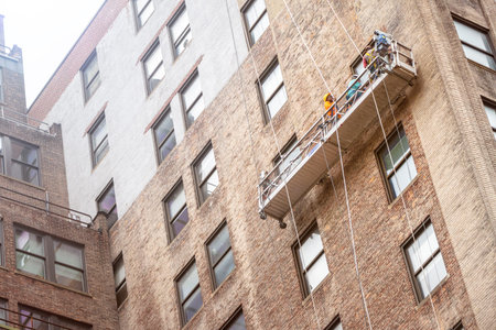 An image of workers hanging on a house facade in New York