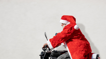 An image of a man on a motorbike in a typical Santa Claus costumeの写真素材