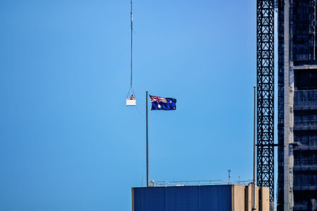 An image of a construction worker in a crane gondola near the Australia flag