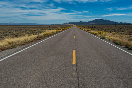Highway in the USA leading through the deserts of Nevada to some mountains and hills in the...