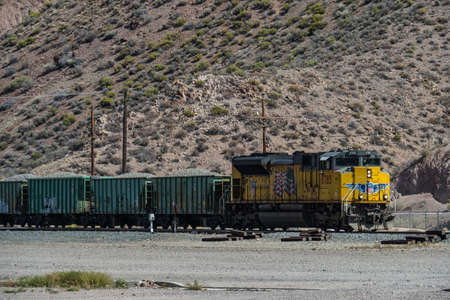 Caliente, Nevada/USA - 29 September 2018: Yellow american type fright train passing a villageのeditorial素材