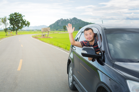 Asian man driving car and show his hand for greetの写真素材