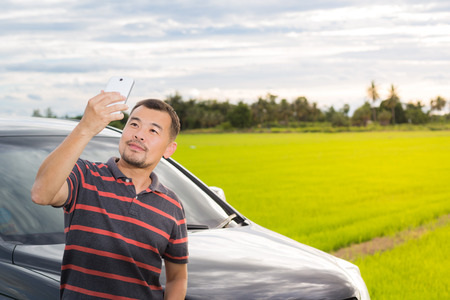 Asian man taking selfie beside his carの写真素材