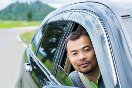 Asian man sitting in car and looking out of the carの写真素材