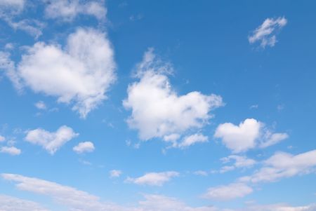 Beautiful blue sky with some romantic heart shaped clouds.の写真素材