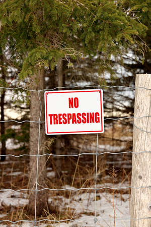 No Trespassing Sign Posted on a Wire Fence in a Rural Settingの写真素材
