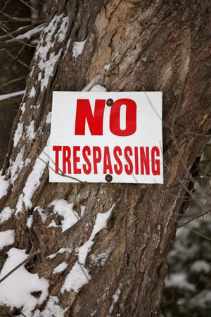 No Trespassing Sign Posted on a Tree Trunk in a Rural Settingの写真素材