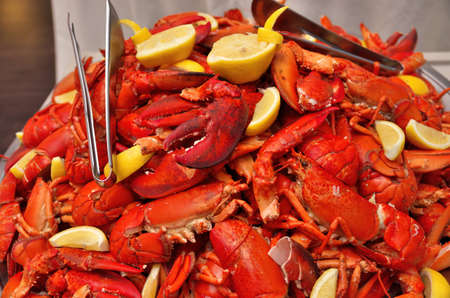 Full Frame Image of cooked lobsters with fresh lemon wedges and serving tongs.の写真素材