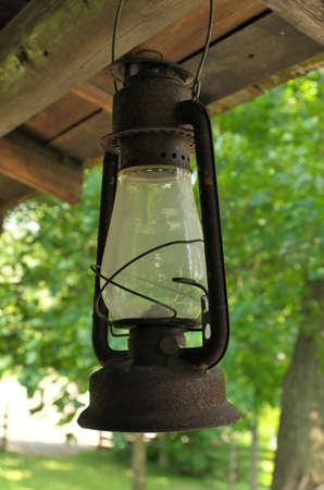 Rusty Kerosene oil lamp hanging from a rustic wooden porchの写真素材