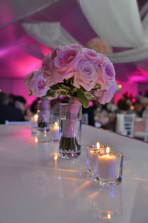Beautiful wedding bouquet flowers on table at tent reception with pink and purple dramatic lightingの写真素材