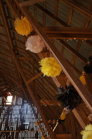 Yellow Black and White Tissue Pompom Decorations Dress up the Inside of a Rustic Barn for a Danceの写真素材