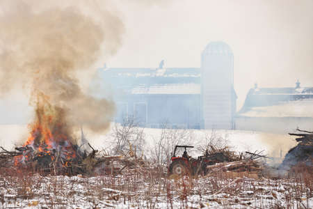 Tractor Moves Brush During a Controlled Burn on a Farm Property to Increase Arable Landの写真素材