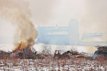 Tractor Moves Brush During a Controlled Burn on a Farm Property to Increase Arable Landの写真素材