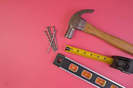 Flatlay of Hammer, Nails, Tape Measure and Level Isolated on a Pink Backgroundの写真素材