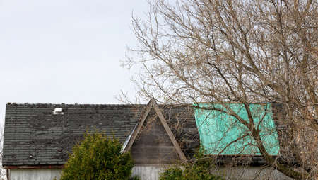 Residential Roof in Desperate Need of Repair or Replacement with peeling shingles and Tarpの写真素材