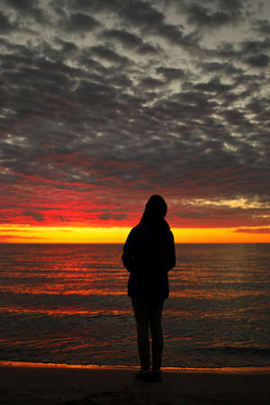 A Young Adolescent Girl Looks up in Awe, Wonder, and Admiration at a Magnificent Sunset Skyの写真素材
