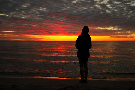 A Young Adolescent Girl Looks up in Awe, Wonder, and Admiration at a Magnificent Sunset Skyの写真素材