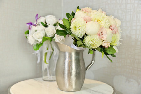 Beautiful Wedding Bouquets in Pitchers of Water on End Table Indoorsの写真素材