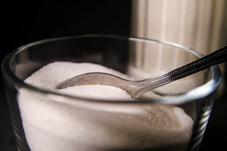 Sugar Close-up with silver spoon and soft vintage sugar jar in isolated background.