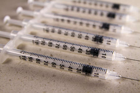 Image depicts a Row of Medical Syringes in an Abstract Clinical Setting.の写真素材