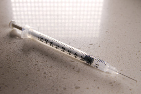 a medical syringe in a clinical setting with abstract overhead light reflection in frame.の写真素材
