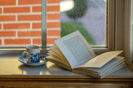 Tea cup and book in the windowの写真素材
