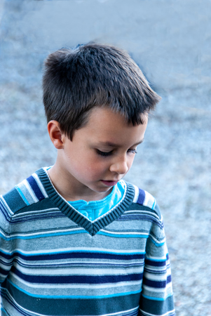 Boy with blue striped sweater looking downの写真素材
