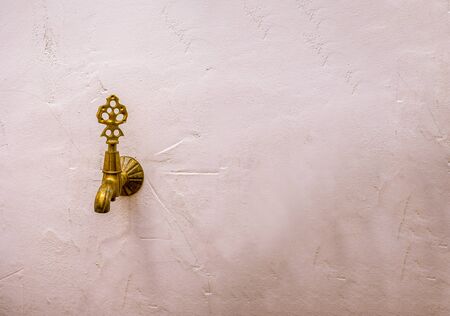 Antique bronze faucet on a white wall.の写真素材