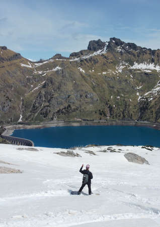 Man with snowboard in the mountains and in the background the Fedaia Lake in the Dolomites, Marmolada. Wintertimeの写真素材