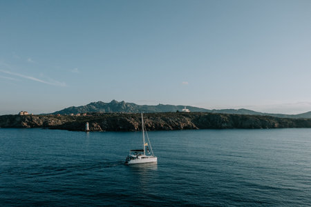 A catamaran sails past Faro di Capo Ferro. Great light and mood Sardinia. 2のeditorial素材