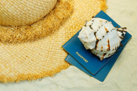 Straw hat, seashell and passports on the sandの写真素材