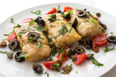 Boiled cod fillets with black olives and tomatoの写真素材