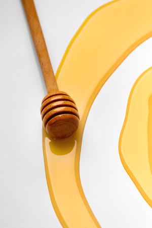 Wooden dipper with honey isolated on a white background. Golden organic floral honey natural. Abstract illustration of honey and dipperの写真素材