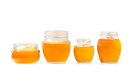 Honey in glass jars. Organic honey in jars on a white background. Open jars with honey one on top isolation. Conceptual composition of honey jars.の写真素材