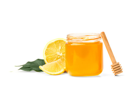 Honey in a glass jar and lemon with leaves on a white background. Open jar with honey, lemon and dipper on isolation.の写真素材