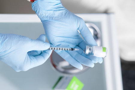 Syringe in the hands of a beautician. Aesthetic cosmetology. Hands in blue gloves and a syringe with...