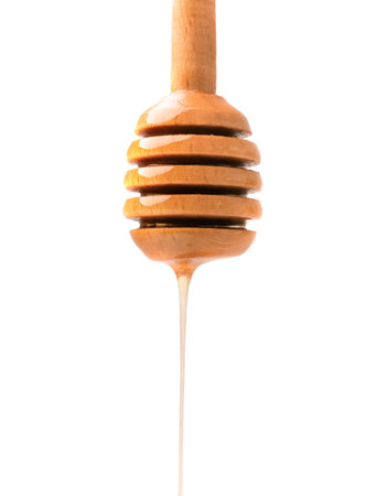 Wooden dipper and pouring honey on a white background. Honey is poured from a wooden stick on the isolation close-up.の写真素材