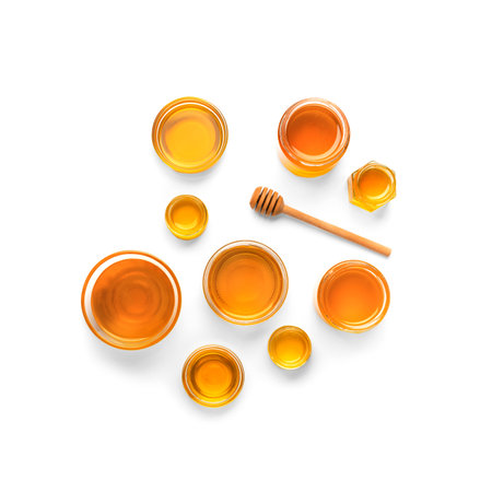 Creative composition of honey jars and dipper on isolation. Honey in a glass dish of different sizes and a stick for honey on a white background. organic products. beekeeping products.の写真素材