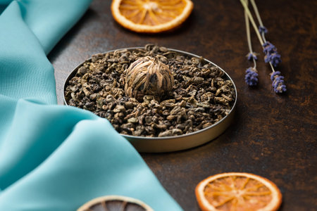 Composition of green, flower tea and dried orange slices on blue and brown backgrounds. Large-leaf tea, dried flowers and citrus chips on contrasting backgrounds.の写真素材