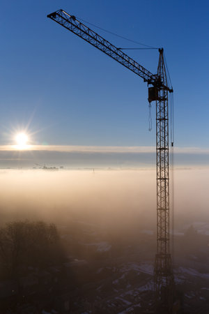 Construction crane in the fog in the morning. Sunrise, morning fog, construction site, tower crane. Mystical foggy morning in the city at dawn. urban landscape.の写真素材