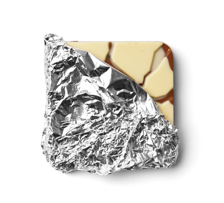 Chocolate bar in silver foil half unfolded on a white background top view. Chocolate in foil partially unwrapped on insulation.の写真素材