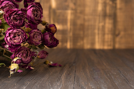 Bouquet of dry pink roses on a dark wooden background close-up. Concept of loneliness or age. Sadness, unhappy love.の写真素材