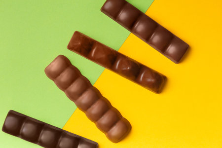 Whole bars of dark and milk chocolate on a bright yellow, green background top view. Chocolate on contrasting backgrounds.の写真素材