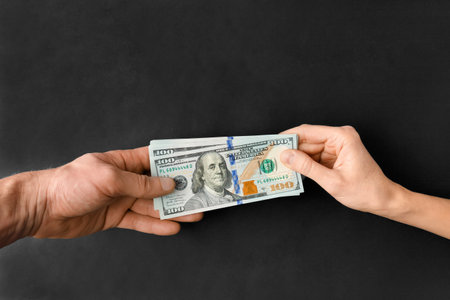 Dollars are passed from hand to hand on a black background with space for text. The concept of corruption, bribery, lending.の写真素材