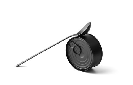 Black matte round closed tin can and black spoon on a white background isolated, tinned food, canned food, preserves.の写真素材