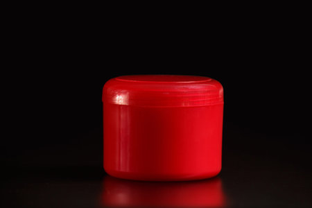 Pink plastic jar for cosmetic products for face and body skin care, hair, isolated on a black...