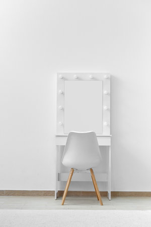 White dressing table for make-up with a large mirror and lamps, a white chair against the background of the wall. Makeup artist workplace, modern dressing room.の写真素材