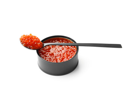 Red salmon caviar in a black tin can and in a black decorative spoon on a white background. Useful delicacy seafood, canned fish.の写真素材