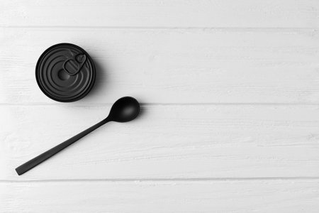 Black matte round closed tin can and black spoon on gray wooden background top view with space for text, tinned food, canned food, preserves.の写真素材
