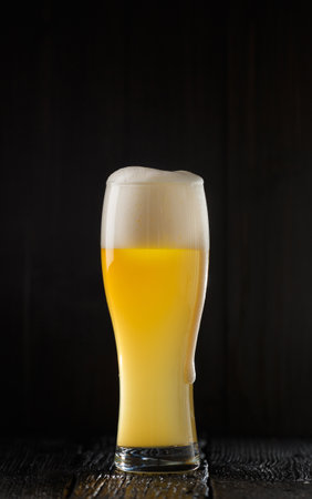 A glass of light beer with a beautiful dense foam on a dark background, copy spaceの写真素材